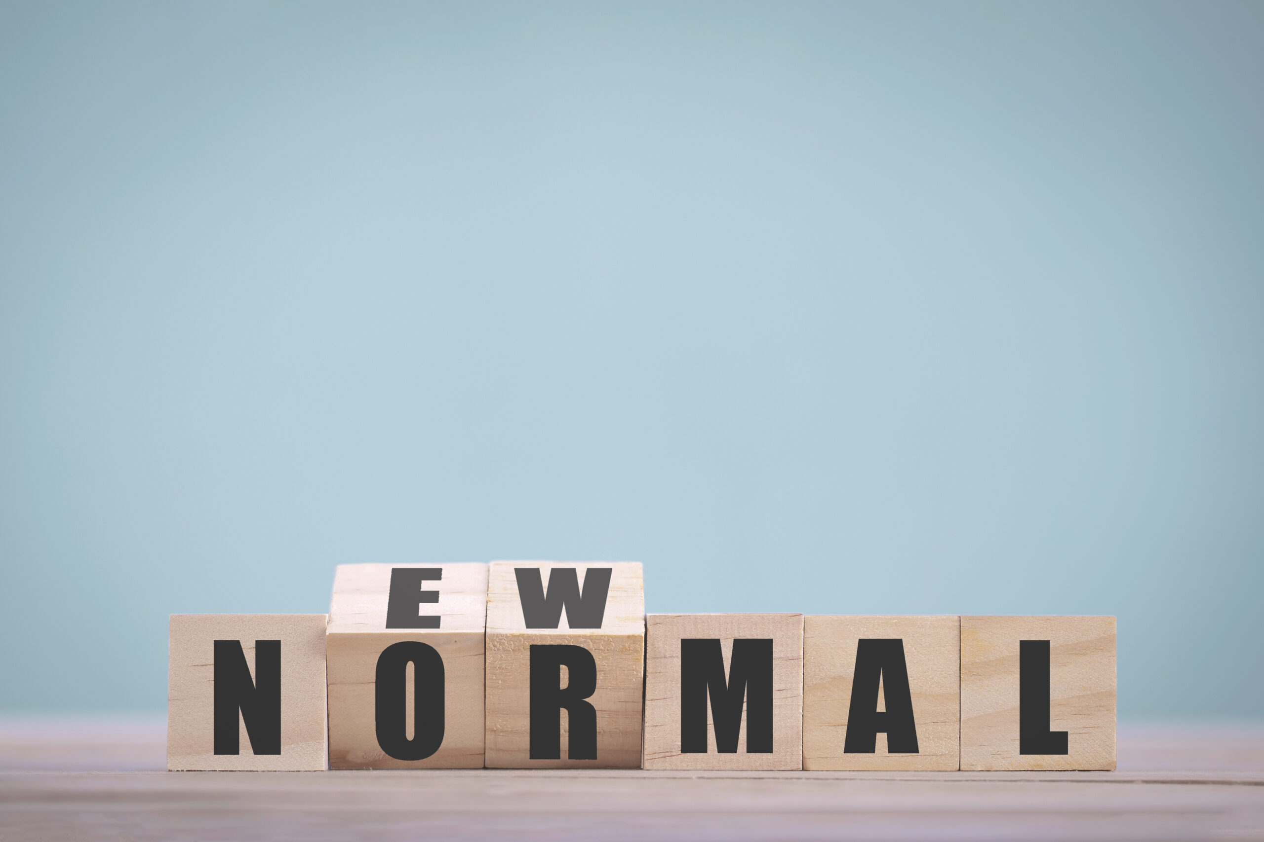 A wooden block that says new normal